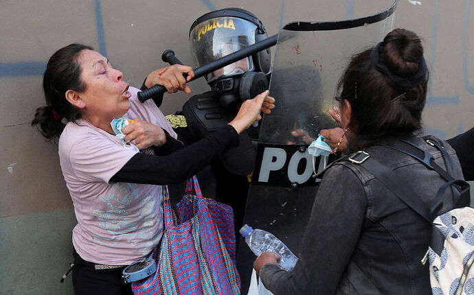 Deux femmes qui manifestaient lundi à Lima pour exiger la dissolution du Congrès péruvien aux prises avec un policier anti-émeutes. REUTERS/Sebastian Castaneda